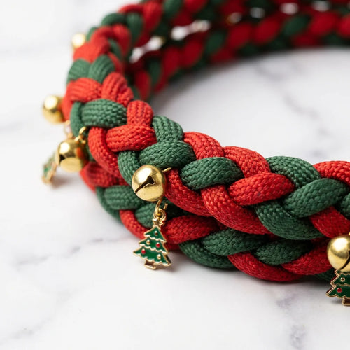Close-up detail of Christmas braided rope leash showing red green weave pattern with golden bells and tree charms