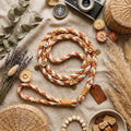 Flat-lay of braided cotton leash with flower charms on linen with dried flowers